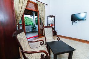 Chami Villa Bentota في بينتوتا: غرفة معيشة فيها كرسيين وطاولة وتلفزيون