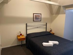 a bedroom with a bed with two towels on it at Baden Lodge Motel - PRIVATE SPA Bath in Rotorua