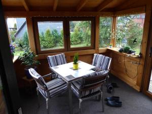 une table et des chaises dans une pièce avec fenêtres dans l'établissement Eifelwaldhäuschen, à Blankenheim