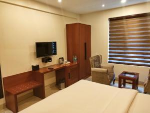 1 dormitorio con 1 cama y escritorio con TV en Holy River Hotel, en Rishīkesh