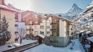 un hôtel dans les montagnes avec de la neige au sol dans l'établissement Matthiol Appartements, à Zermatt