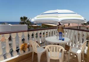 a table and chairs with an umbrella on a balcony at Bahia El Calon in San Juan de los Terreros