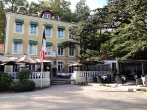 a large yellow building with a flag in front of it at Le Cèdre de Soyons in Soyons