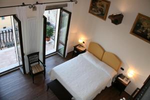 1 dormitorio con cama blanca y balcón en Meublé il Riccio, en Montepulciano