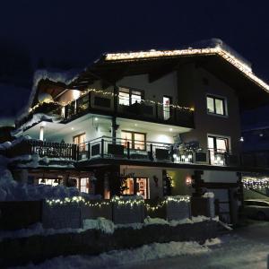 een huis met kerstverlichting in de sneeuw bij Apart Edelweiss in Hippach