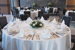 a round table with white tablecloths and silverware at The Teak Hotel in Mae Sot