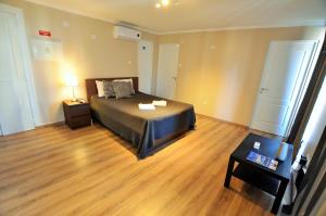 a bedroom with a bed and a wooden floor at Suites & Apartments - DP Setubal in Setúbal