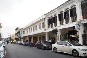 a white car parked on the side of a city street at Chino Town at Yaowarat Phuket - SHA Plus in Phuket Town