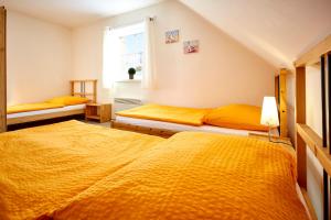 2 Betten in einem Zimmer mit gelber Bettwäsche in der Unterkunft Apartmány Happy Klínovec in Loučná pod Klínovcem