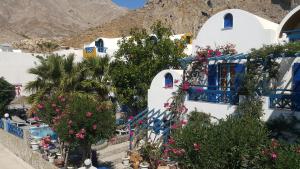 a group of white buildings with flowers and trees at DARZENTA ATHINA APARTMENTS Perissa in Perissa