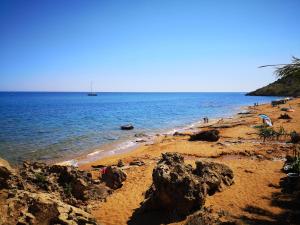 a beach with rocks and the ocean and a boat at Village Camping Fico D'India in Ovile la Marina