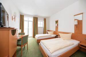 ビットブルクにあるHotel Bitburger Hofのベッド2台とデスクが備わるホテルルームです。