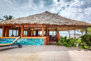 un complexe avec un grand parasol en paille et une piscine dans l'établissement Seaview - Caribe Island, à San Pedro