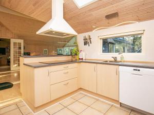 a kitchen with white cabinets and a wooden ceiling at 12 person holiday home in R dby in Kramnitse