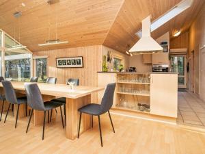 an open kitchen and dining room with a large wooden table and chairs at 12 person holiday home in R dby in Kramnitse