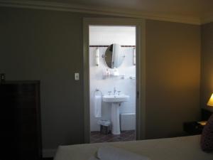 Heritage Guesthouse في ساوث ويست روكس: حمام مع حوض ومرآة