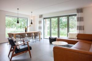 a living room with a couch and a table at Aan Noordzee Villa Veranda in Sint Maartensvlotbrug