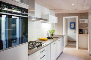 a kitchen with white cabinets and a stove top oven at Aan Noordzee Vakantiehuis aan zee 4 Personen in Sint Maartensvlotbrug