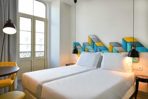 a bedroom with a large white bed with a colorful headboard at Caçarola Dois - Alojamento local in Figueira da Foz