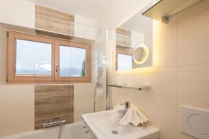 La salle de bains est pourvue d'un lavabo et d'une douche. dans l'établissement Angerer Alpine Suiten und Familienappartements Tirol, à Reith im Alpbachtal