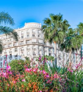 a building with palm trees and flowers in front of it at Croisette Palais Miramar Cannes Imperial in Cannes