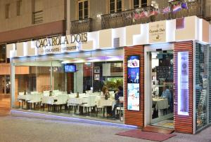 a restaurant with white tables in the front of it at Caçarola Dois - Alojamento local in Figueira da Foz