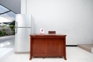 un frigorifero seduto accanto a un tavolo di legno accanto a un edificio di OYO 2058 Griya Ria a Solo