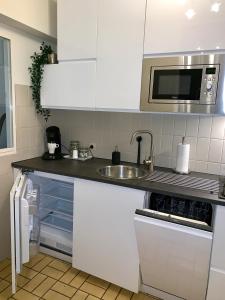 a white kitchen with a sink and a microwave at Studio De Strandsuite in Ostend