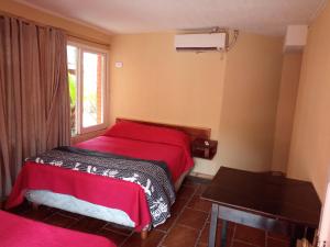 a bedroom with a red bed and a window at Sweet Guest House in Puerto Iguazú