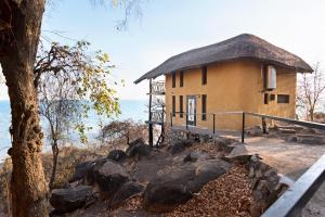 a building with a thatched roof next to the water at Safari Beach Lodge in Senga