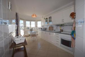 a kitchen with white cabinets and a table in it at Carob By Algartur in Santa Luzia