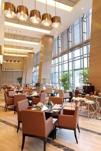 um restaurante com mesas e cadeiras e janelas grandes em Grand Mercure Jinan Sunshine em Jinan