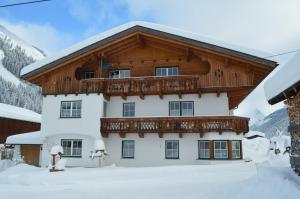 ein Haus mit einem Holzdach im Schnee in der Unterkunft Apart Lorenz in Häselgehr