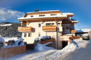 une maison dans la neige avec une clôture dans l'établissement Alp Residence Pelegrin, à San Vigilio Di Marebbe