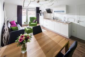 cocina y sala de estar con mesa de madera y sillas en Appartement Haus Bracht- direkt am Kurplatz en Juist