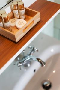 a bathroom sink with a wooden tray with cosmetics at Apartamentos com História in Guimarães