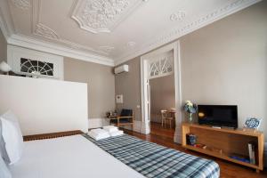 um quarto com uma cama e uma televisão na parede em Apartamentos com História em Guimarães