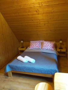 a bed in a wooden room with two pillows at Całoroczne Domki "Stokrotka" in Solina