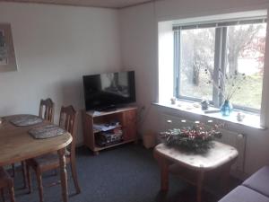 ein Wohnzimmer mit einem Tisch und einem TV sowie einem Tisch und Stühlen in der Unterkunft Lindholt in Fjerritslev