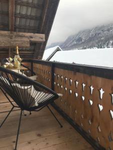 una silla en el balcón de una cabaña con nieve en LAKE HOUSE BOHINJ, en Bohinj