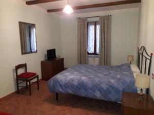 una camera con letto, sedia e televisore di Relax nel tufo a Pitigliano