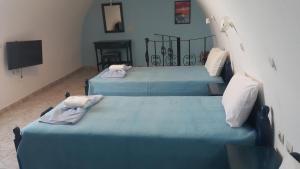 two blue beds in a room with a television at DARZENTA ATHINA APARTMENTS Perissa in Perissa