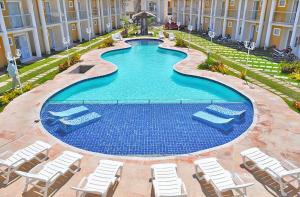 a swimming pool with lounge chairs and a hotel at FLAT RESID MONT CARMELO in Porto Seguro