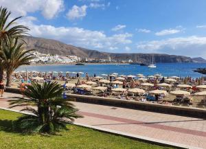 - une plage avec des parasols et des personnes sur la plage dans l'établissement Apartamento Torres del Sol, à Arona