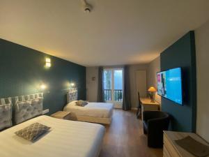 a hotel room with two beds and a flat screen tv at Hôtel des Chazes in Saint-Jacques-des-Blats