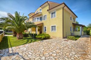a large yellow house with a stone driveway at Apartments Gilly 1 in Premantura