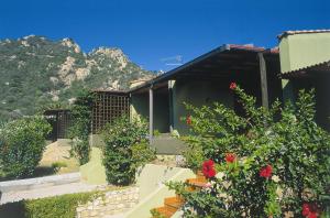 ein Haus mit Blumen und einem Berg im Hintergrund in der Unterkunft Appartamenti Costa Rei in Monte Nai