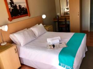 a bedroom with a white bed with towels on it at Marle' Lodge in Germiston