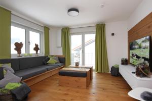 ein Wohnzimmer mit einem Sofa und einem TV in der Unterkunft Alpenglück in Wertach