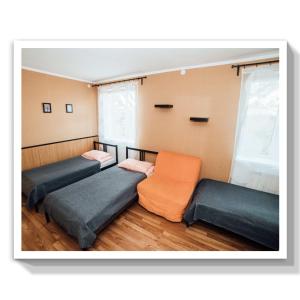 a room with three beds and an orange chair at Guest House Marina in Il'ich